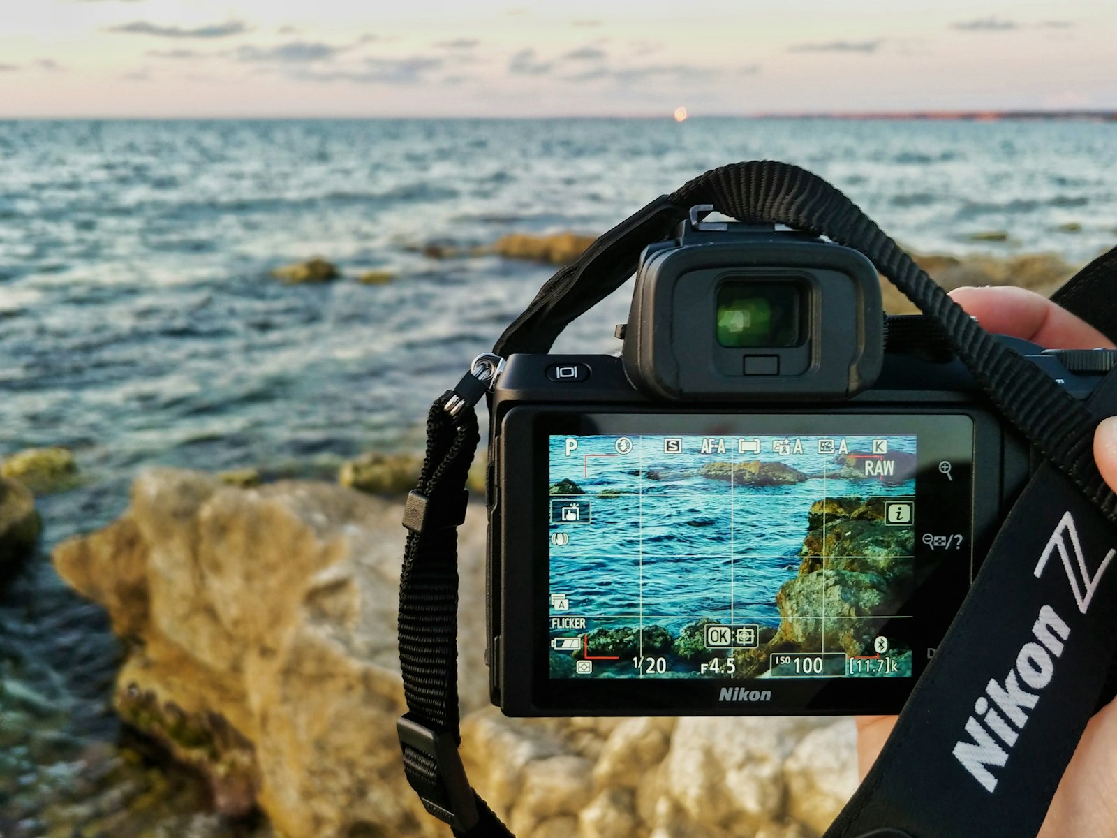 Photographer using a camera to capture a coastal landscape