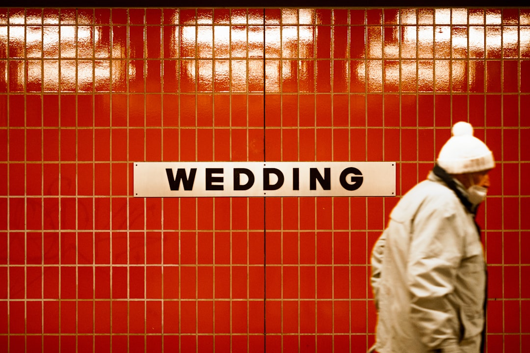 a man walking past a red tiled wall