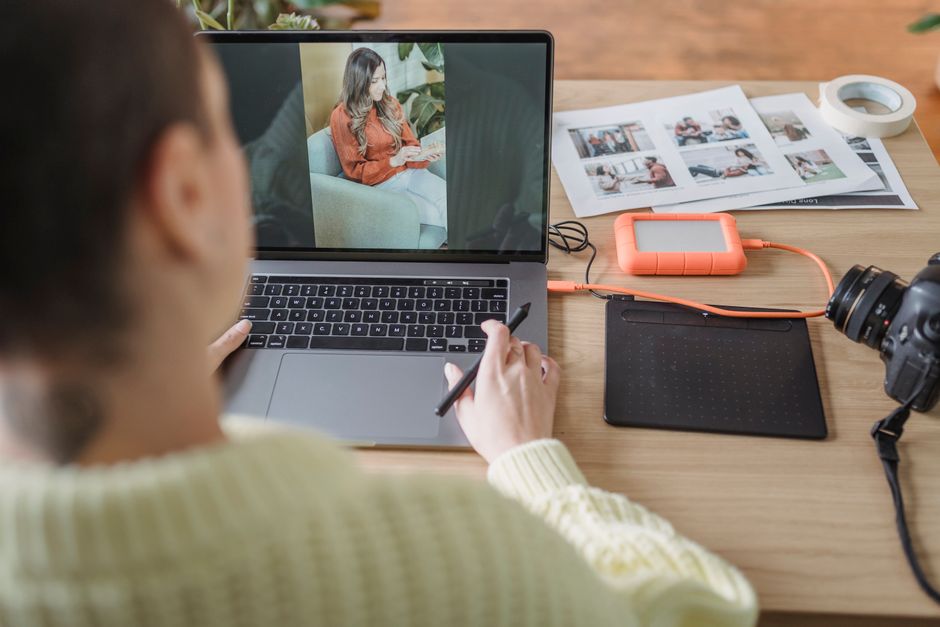 Photographer editing a portrait on a laptop with a pen tablet and printed proofs