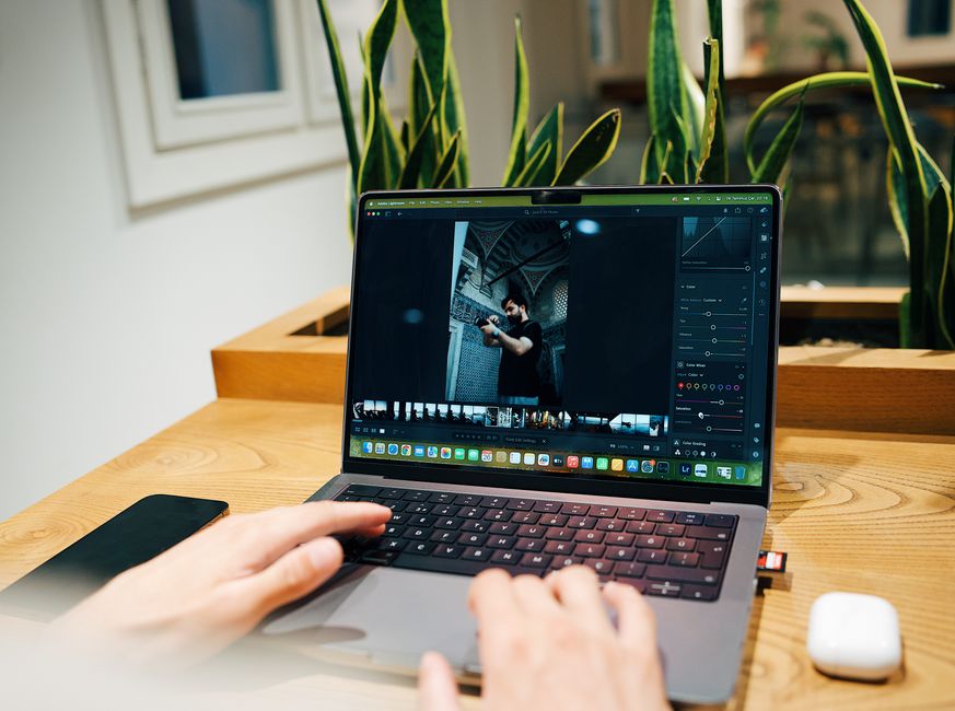 Photographer editing images on a laptop in a modern studio